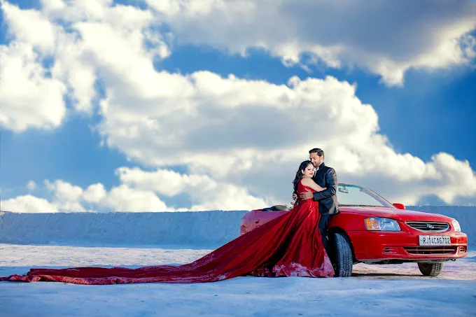 a man and woman in a red car driving on a snowy road