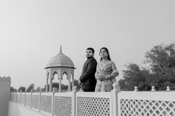 A couple posing elegantly during their pre-wedding shoot in Jaipur, with a historic dome structure in the background, exuding royal charm in black and white.