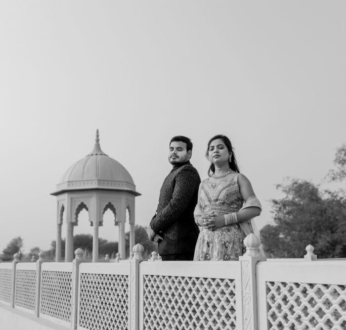 A couple posing elegantly during their pre-wedding shoot in Jaipur, with a historic dome structure in the background, exuding royal charm in black and white.