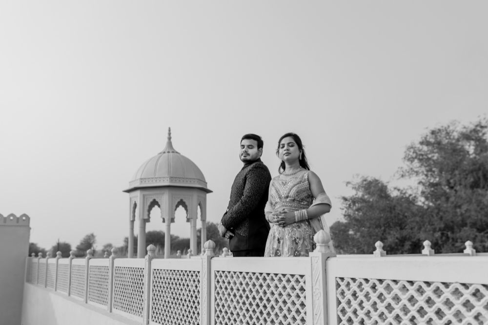 A couple posing elegantly during their pre-wedding shoot in Jaipur, with a historic dome structure in the background, exuding royal charm in black and white.