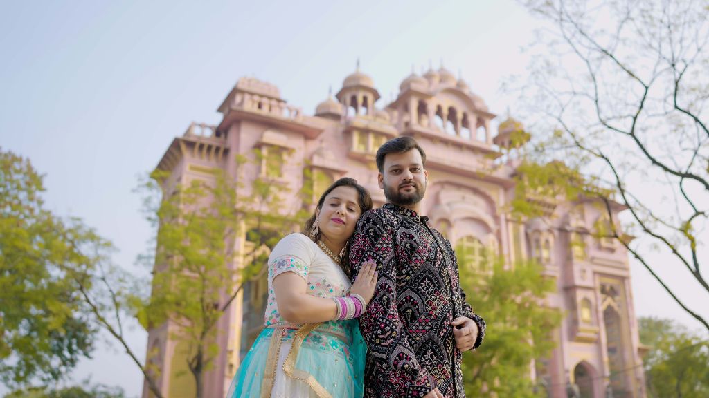 A couple poses in traditional attire for a pre-wedding shoot in front of a beautiful heritage building in Jaipur, Rajasthan.