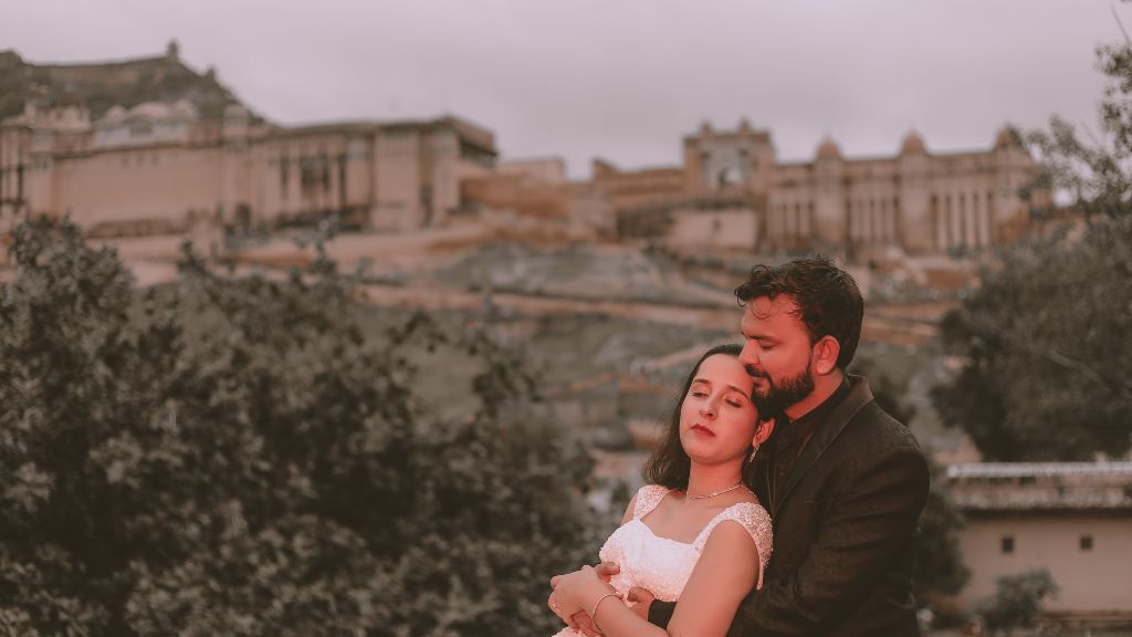 A couple shares an intimate moment with the stunning Amber Fort in the background during their pre-wedding shoot in Jaipur.