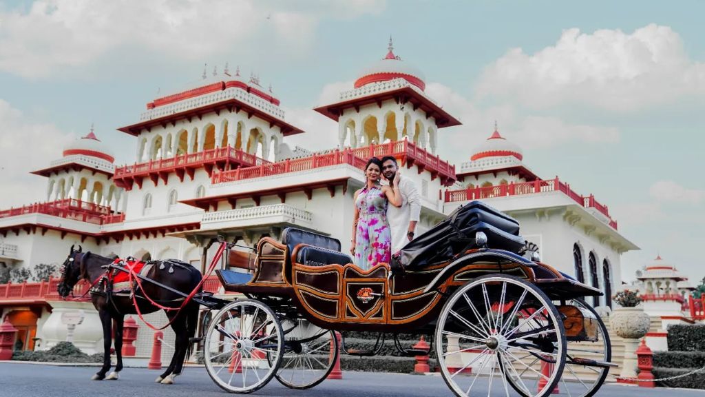  A couple posing for a pre-wedding shoot in  Jaipur front of a majestic palace in Jaipur with a horse-drawn carriage.