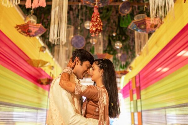 Best Wedding Photographers in JaipurA bride and groom embrace under colorful wedding decorations, surrounded by warm lighting and intricate traditional element