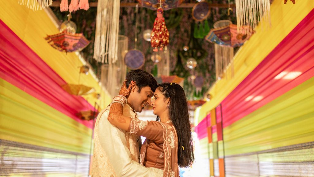 Best Wedding Photographers in JaipurA bride and groom embrace under colorful wedding decorations, surrounded by warm lighting and intricate traditional element