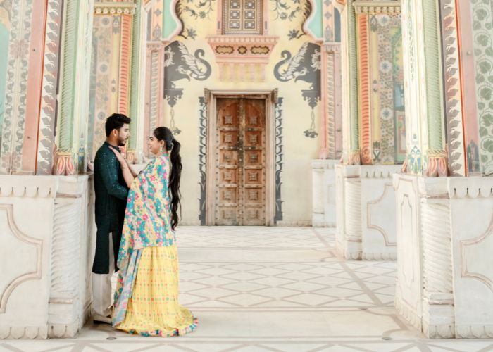 pre-wedding shoot in Jaipur cost Couple posing in traditional attire for a pre-wedding shoot in Jaipur, surrounded by vibrant architecture.