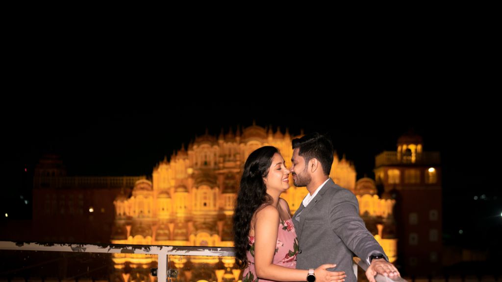 A couple posing romantically in front of the illuminated Hawa Mahal in Jaipur, capturing a stunning pre-wedding shoot with the city's royal heritage as a backdrop.