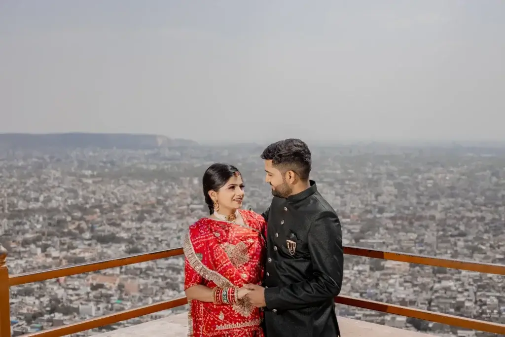 A couple in traditional attire enjoying a breathtaking Pre-Wedding Shoot in Jaipur, standing on a terrace with a panoramic city view in the background.