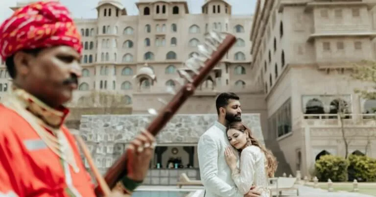 Romantic couple during a pre-wedding shoot at Fairmont Jaipur with a traditional Rajasthani musician in the foreground