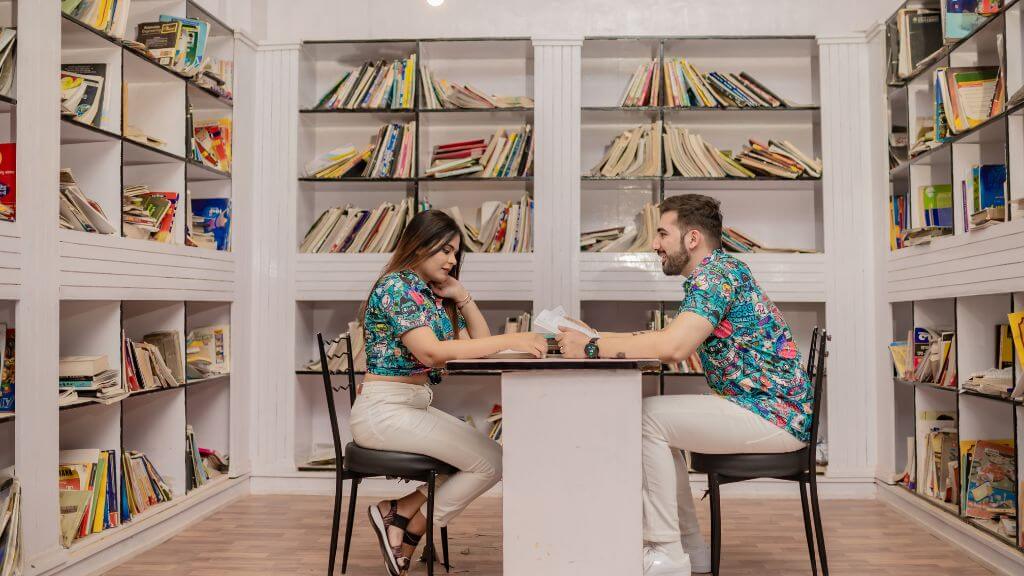 Couple in matching outfits sitting in a library-themed pre wedding photoshoot studio in Jaipur