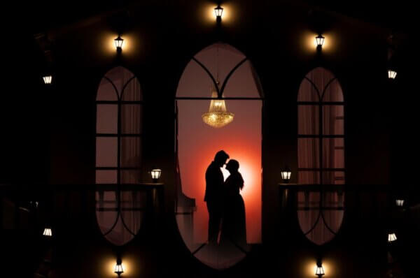 Couple posing in silhouette under chandelier lighting at night in a romantic pre wedding photoshoot studio in Jaipur