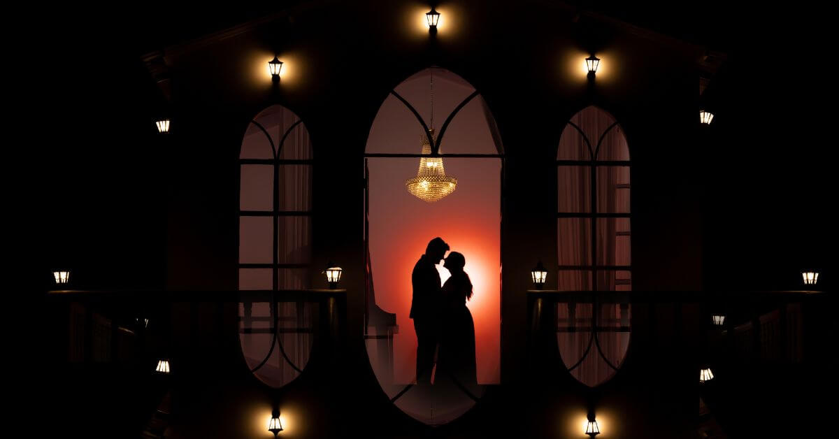 Couple posing in silhouette under chandelier lighting at night in a romantic pre wedding photoshoot studio in Jaipur