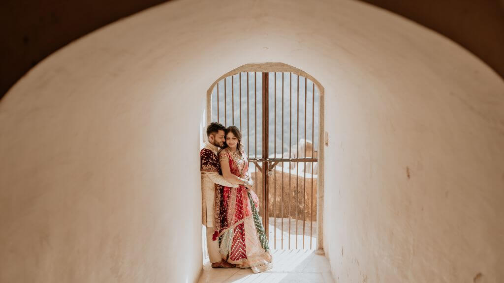 Couple in traditional attire posing inside a heritage arch tunnel with soft lighting, highlighting ideal Pre Wedding Shoot Timing in Jaipur.