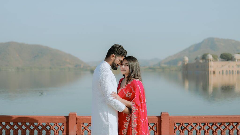 Couple posing at sunset with Jal Mahal reflected in the water during a pre wedding shoot in Jaipur