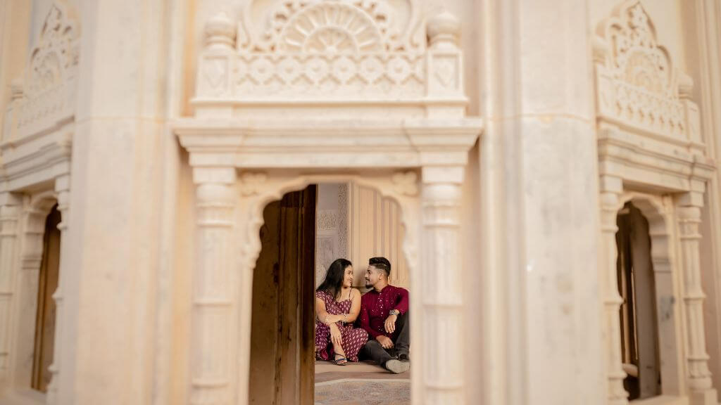 Couple sitting together inside a beautifully carved Rajasthani palace arch during a pre-wedding shoot near Jaipur
