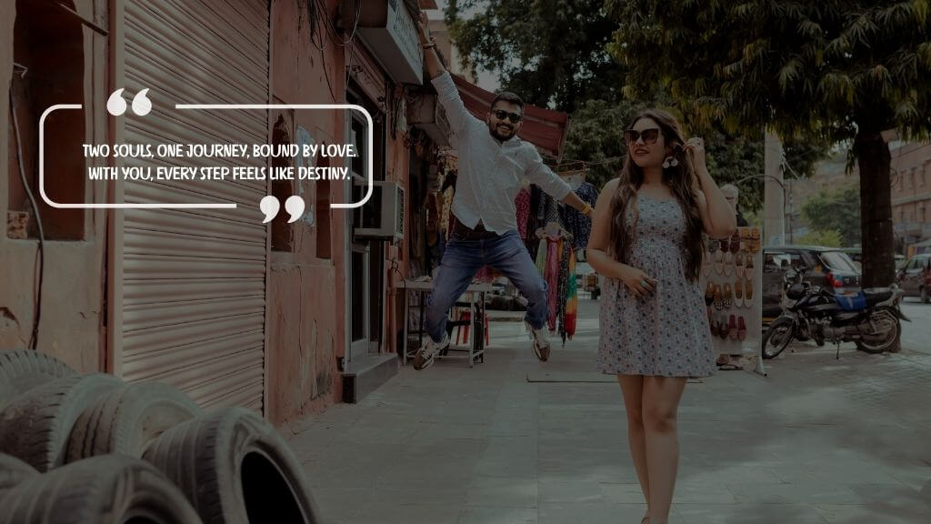 A young couple in casual outfits walking through a local Indian street market; the man jumps playfully while the woman smiles confidently, with an overlaid romantic quote: “Two souls, one journey, bound by love. With you, every step feels like destiny.”

