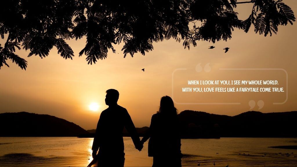 A silhouette of a couple holding hands during sunset beside a peaceful lake, with an emotional quote overlay: “When I look at you, I see my whole world. With you, love feels like a fairytale come true.”