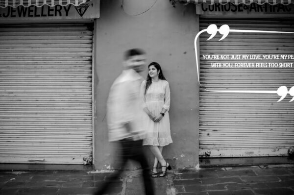 A black and white image of a woman standing by a closed shop shutter while her partner walks past in motion blur, overlaid with the quote: “You’re not just my love, you’re my peace. With you, forever feels too short.” — perfect for couple quotes for wedding content.