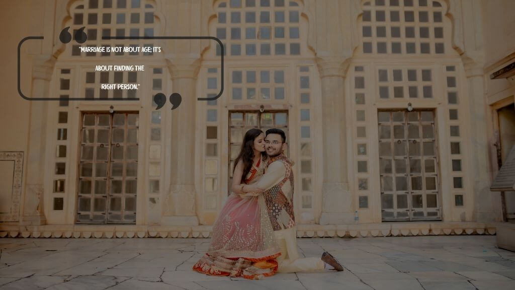 A couple in traditional Indian wedding attire posing romantically in front of a palace-style building with a wedding quote: “Marriage is not about age; it’s about finding the right person.”

