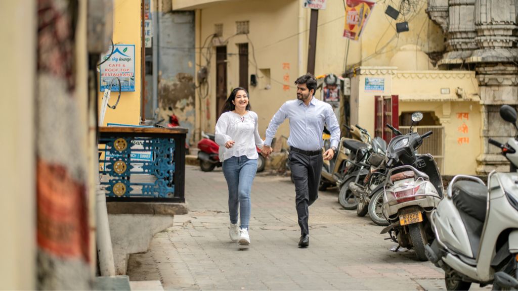Couple walking hand in hand during a pre-wedding shoot in Udaipur with Lake Pichola and heritage palace backdrop